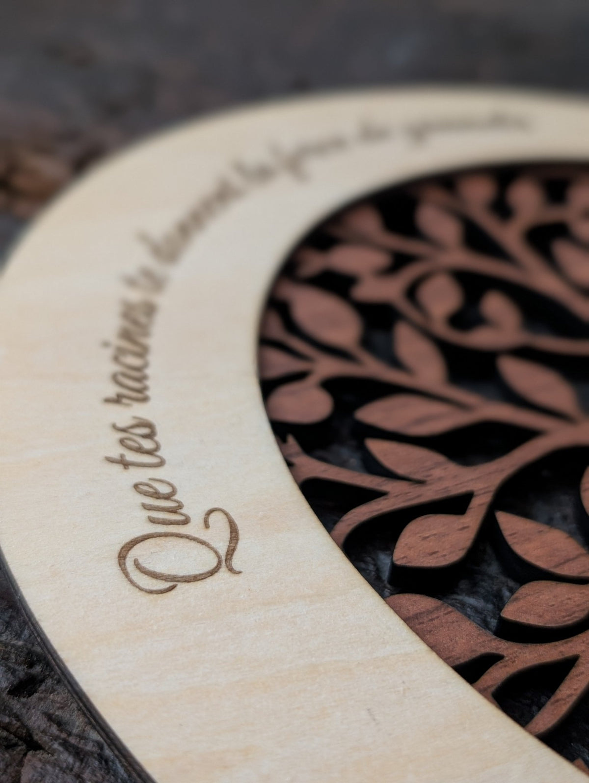 Gros plan du cœur gravé au prénom de l’enfant et des feuilles en bois gravées de prénoms sur l’arbre de vie