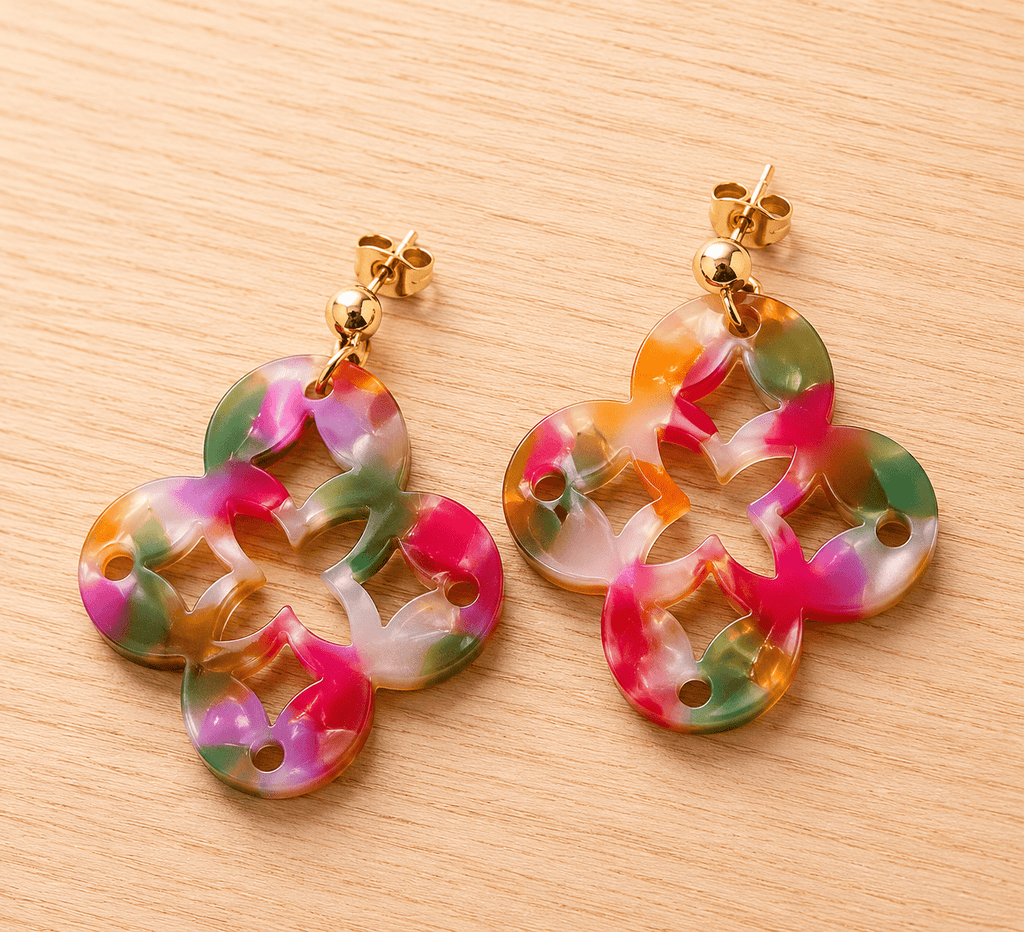 Paire de boucles d'oreilles en résine acrylique multicolore effet marbré, forme trèfle découpé, puces boules dorées, fond bois clair