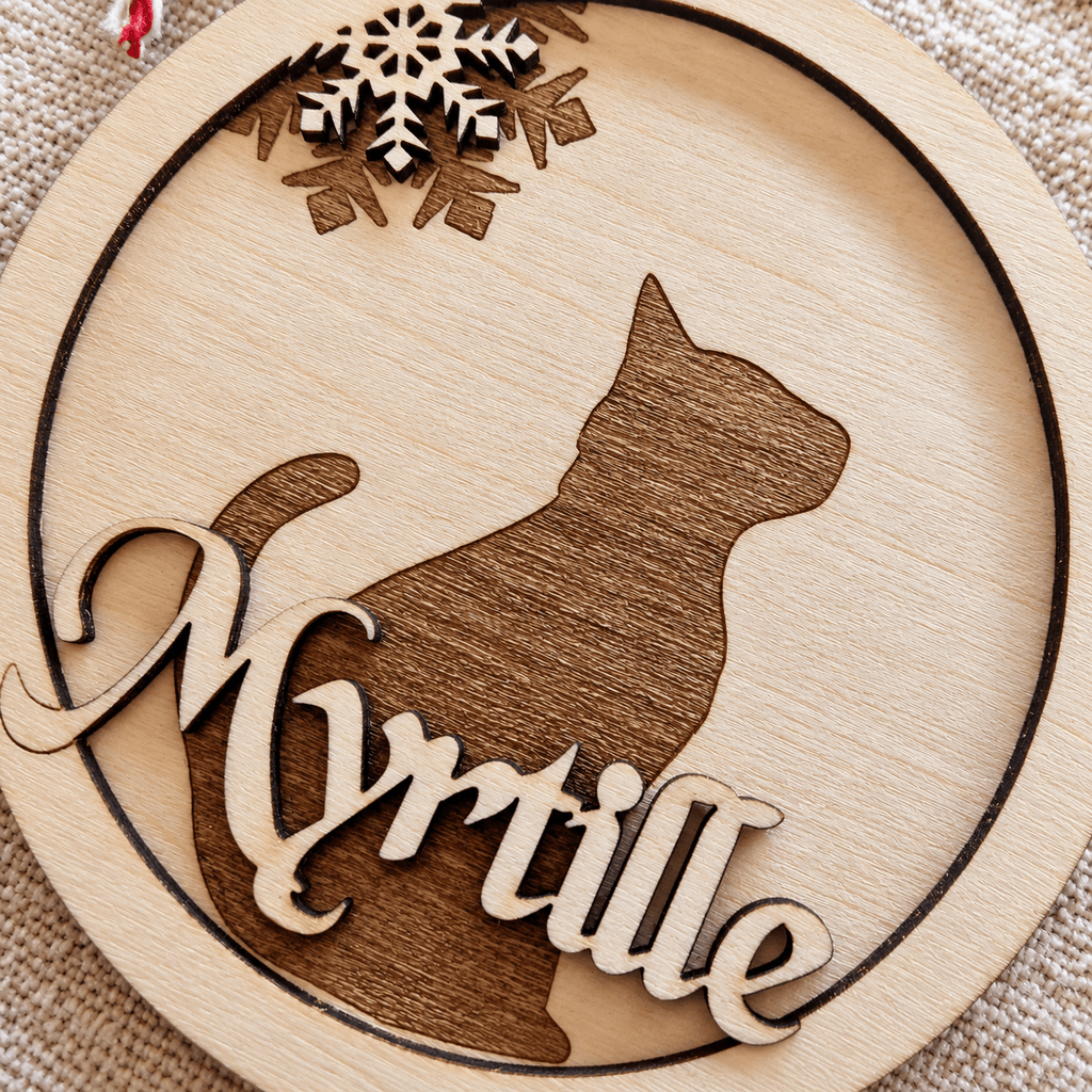 Gros plan sur la boule de Noël ronde en bois avec silhouette de chat en relief et prénom Myrtille gravé