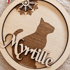 Gros plan sur la boule de Noël ronde en bois avec silhouette de chat en relief et prénom Myrtille gravé