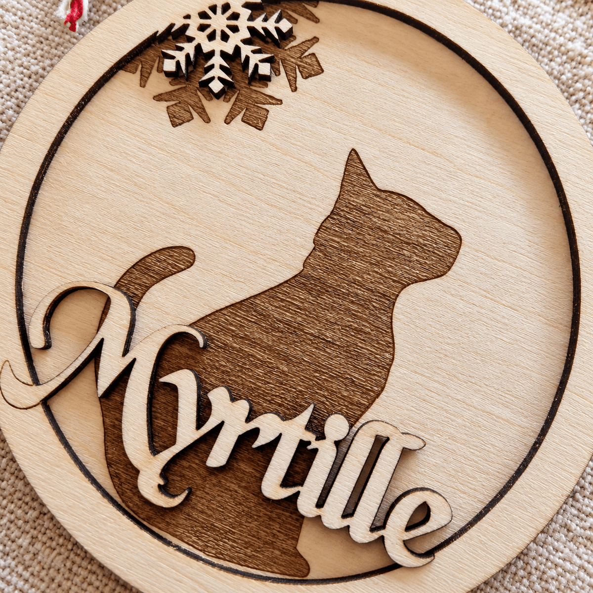 Gros plan sur la boule de Noël ronde en bois avec silhouette de chat en relief et prénom Myrtille gravé