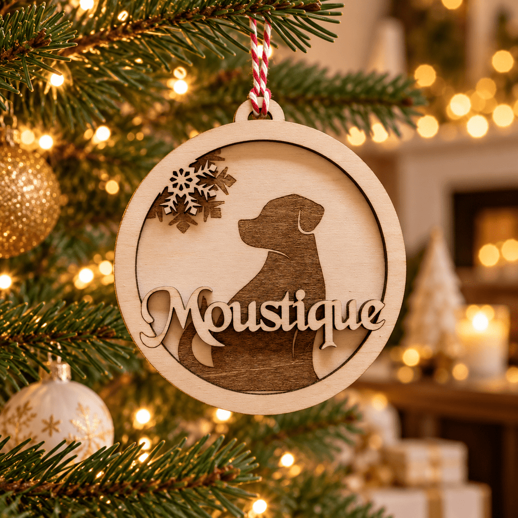 Boule de Noël ronde en bois avec silhouette de chien et prénom Moustique, suspendue dans le sapin