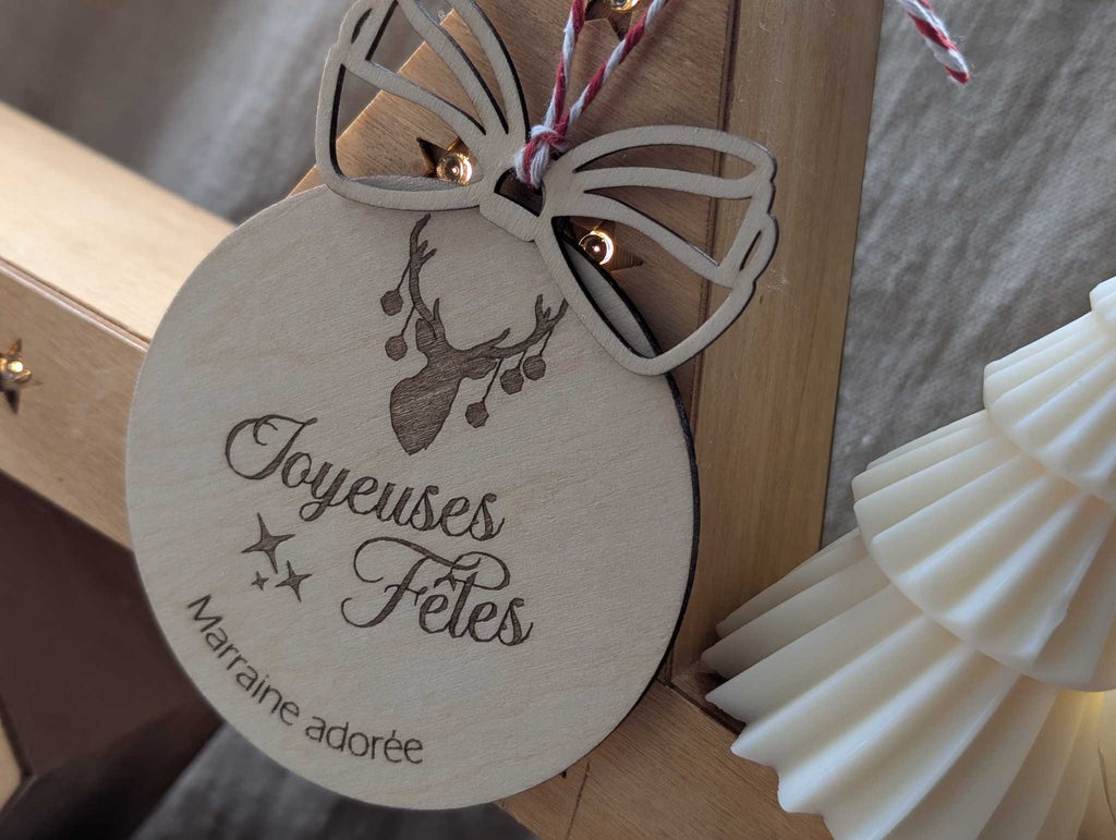 Boule de Noël bois personnalisée élan joyeuses fêtes gravure texte marraine nœud ajouré décoration sapin
