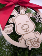Gros plan sur prénom gravé sous Joyeux Noël sur boule en bois avec renne et flocon