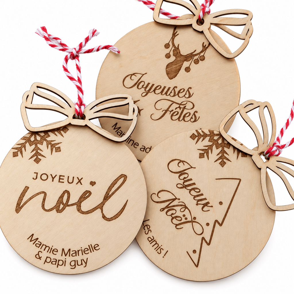 Trois boules de Noël en bois à nœud ajouré en relief, modèles sapin, élan et flocon, avec textes personnalisés gravés, sur fond blanc