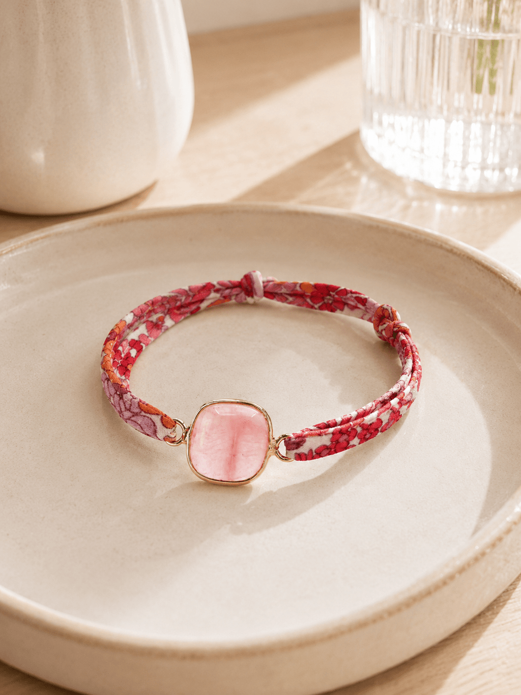 Bracelet ruban Liberty floral rose avec pierre naturelle rose sertie or posé sur coupelle céramique