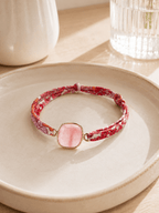 Bracelet ruban Liberty floral rose avec pierre naturelle rose sertie or posé sur coupelle céramique
