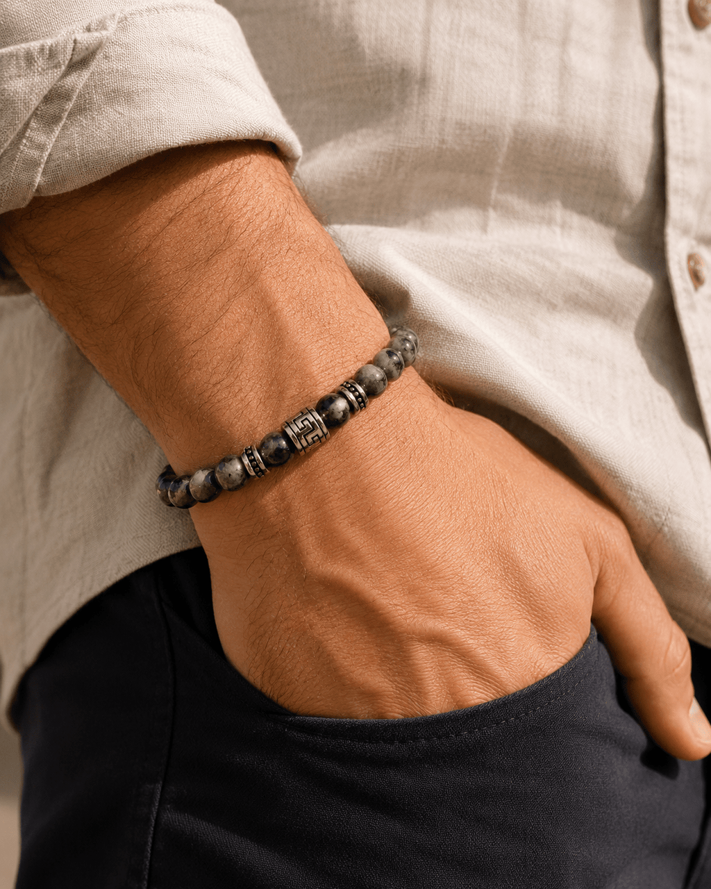 Bracelet homme perles de labradorite naturelles avec accent argenté gravé, porté au poignet d'un homme en chemise lin beige, main dans la poche