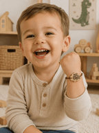 Petit garçon souriant portant un bracelet enfant en bois gravé motif tracteur sur cordon marron ajustable, dans une chambre d'enfant aux tons naturels