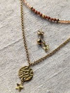 Gros plan sur la délicate étoile striée du collier 2 rangs doré, bijou féminin et raffiné