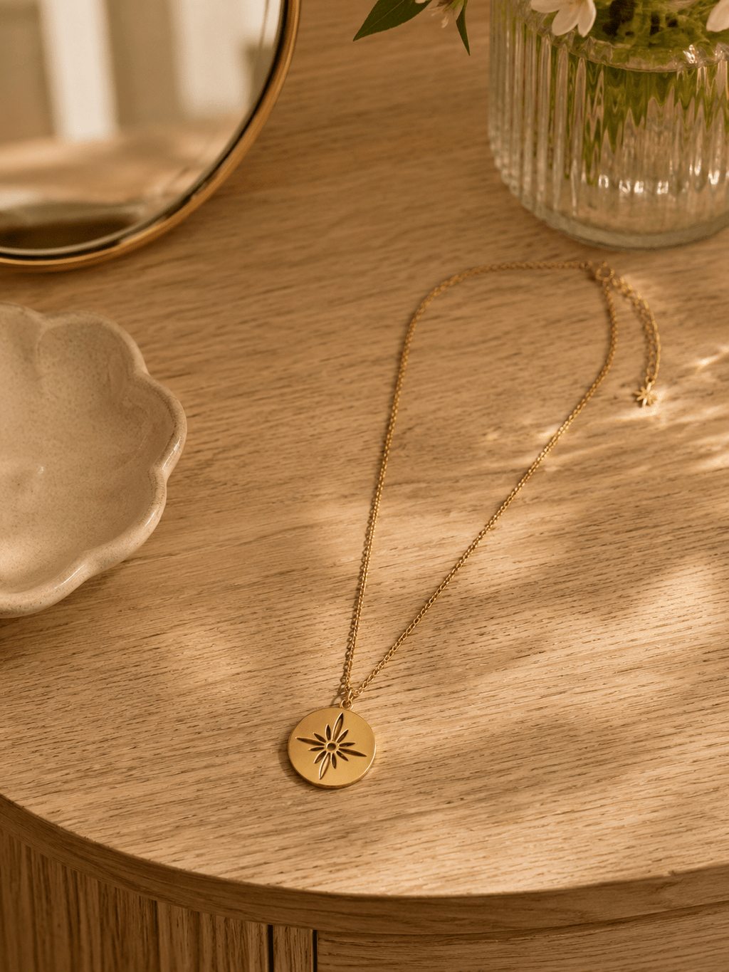 Collier médaillon étoile doré posé sur meuble en bois ambiance lumineuse dorée, bijou artisanal acier
