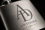 Gros plan gravure laser flasque inox monogramme initiales AD prénom Antoine — cadeau homme élégant premium