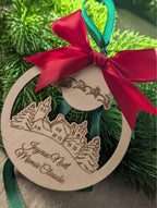 Boule de Noël en bois personnalisée avec prénom sous Joyeux Noël, ruban satin vert et gros nœud rouge satin avec traineau et rennes, collection Artesama