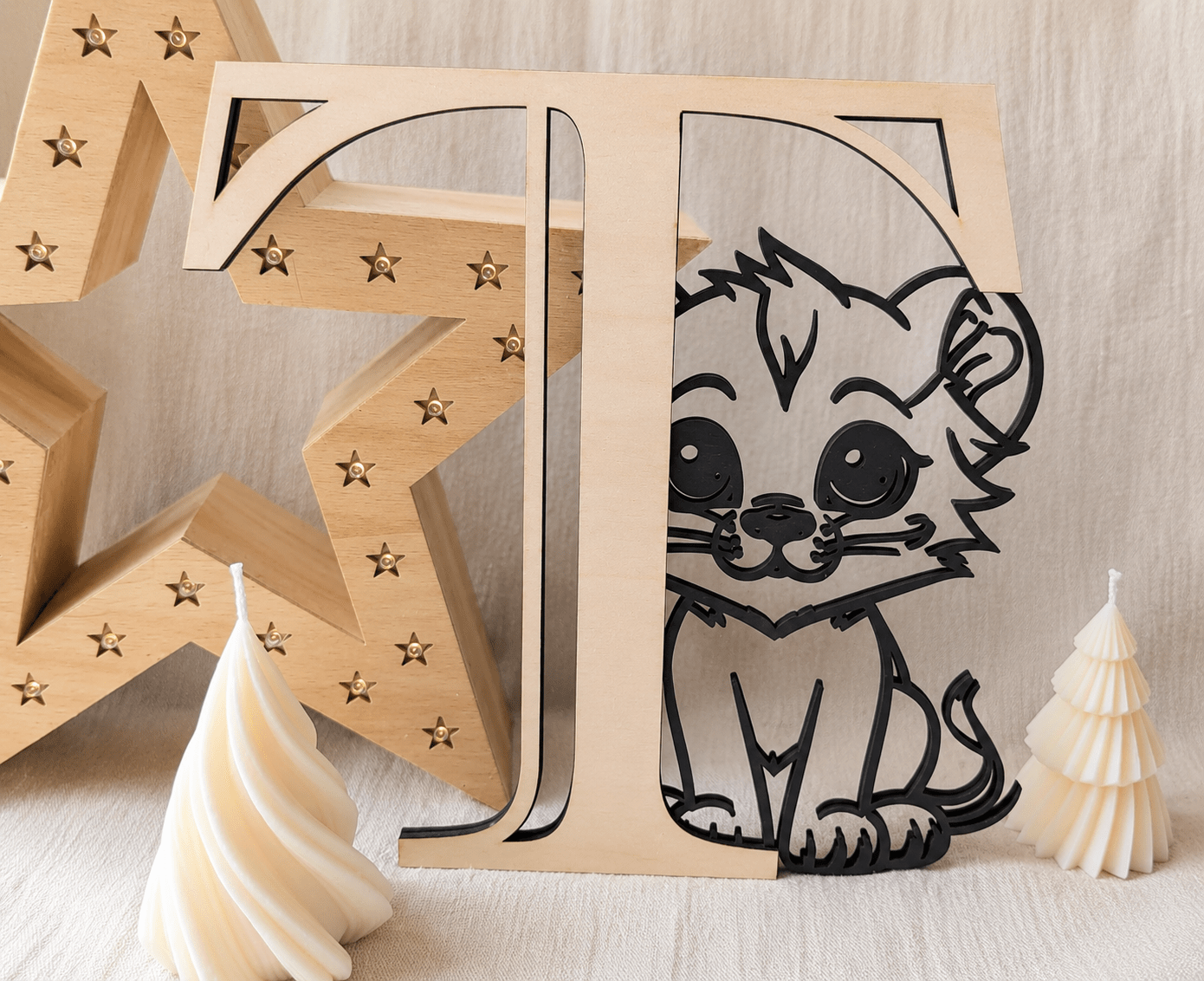 Lettre décorative en bois "T" avec lionceau découpé en noir, posée sur une surface blanche avec étoile lumineuse et bougies, décoration chambre enfant