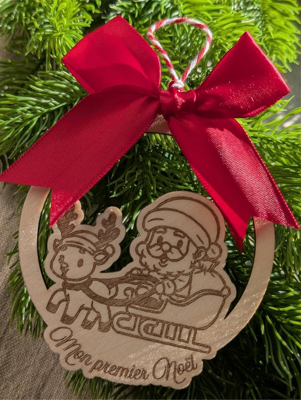 Boule de Noël en bois personnalisée. Mon premier Noël. Modèle avec père Noël dans son traineau et un renne, surmonté d'un joli nœud en satin rouge