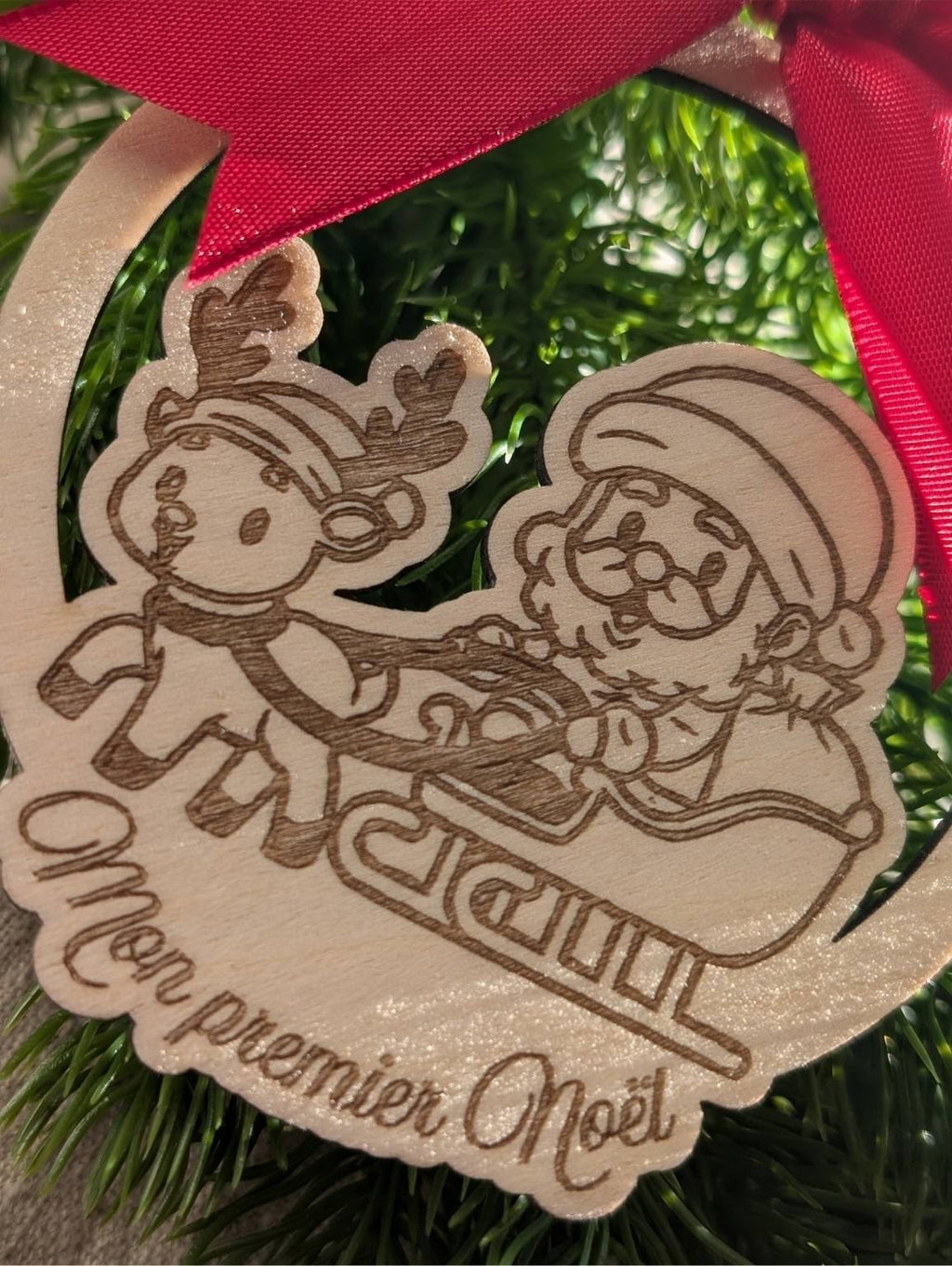 Boule de Noël en bois personnalisée. Mon premier Noël. Modèle avec père Noël dans son traineau et un renne, surmonté d'un joli nœud en satin rouge