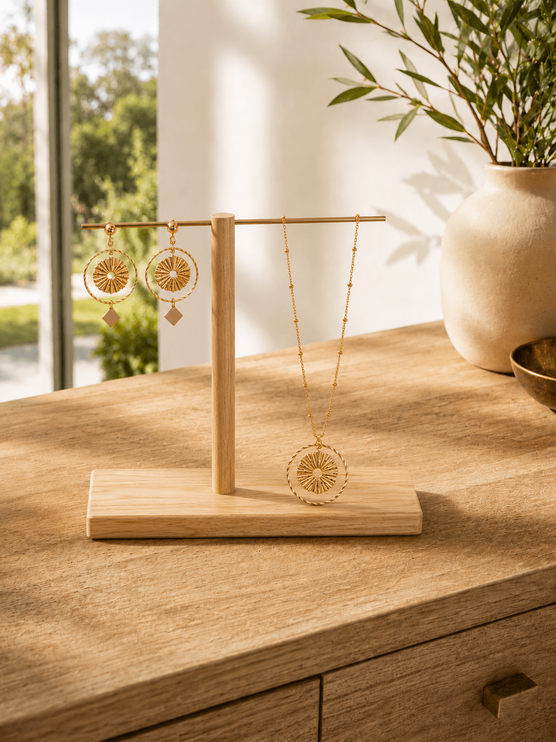 Parure soleil dorée collier et boucles pendantes sur présentoir en bois, bijoux artisanaux acier hypoallergénique