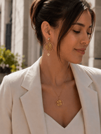 Femme portant une parure soleil dorée boucles pendantes cercle rayonnant et collier médaillon acier doré
