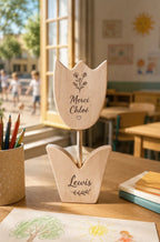 Tulipe en bois gravée "Merci Chloé" posée sur un bureau d'école