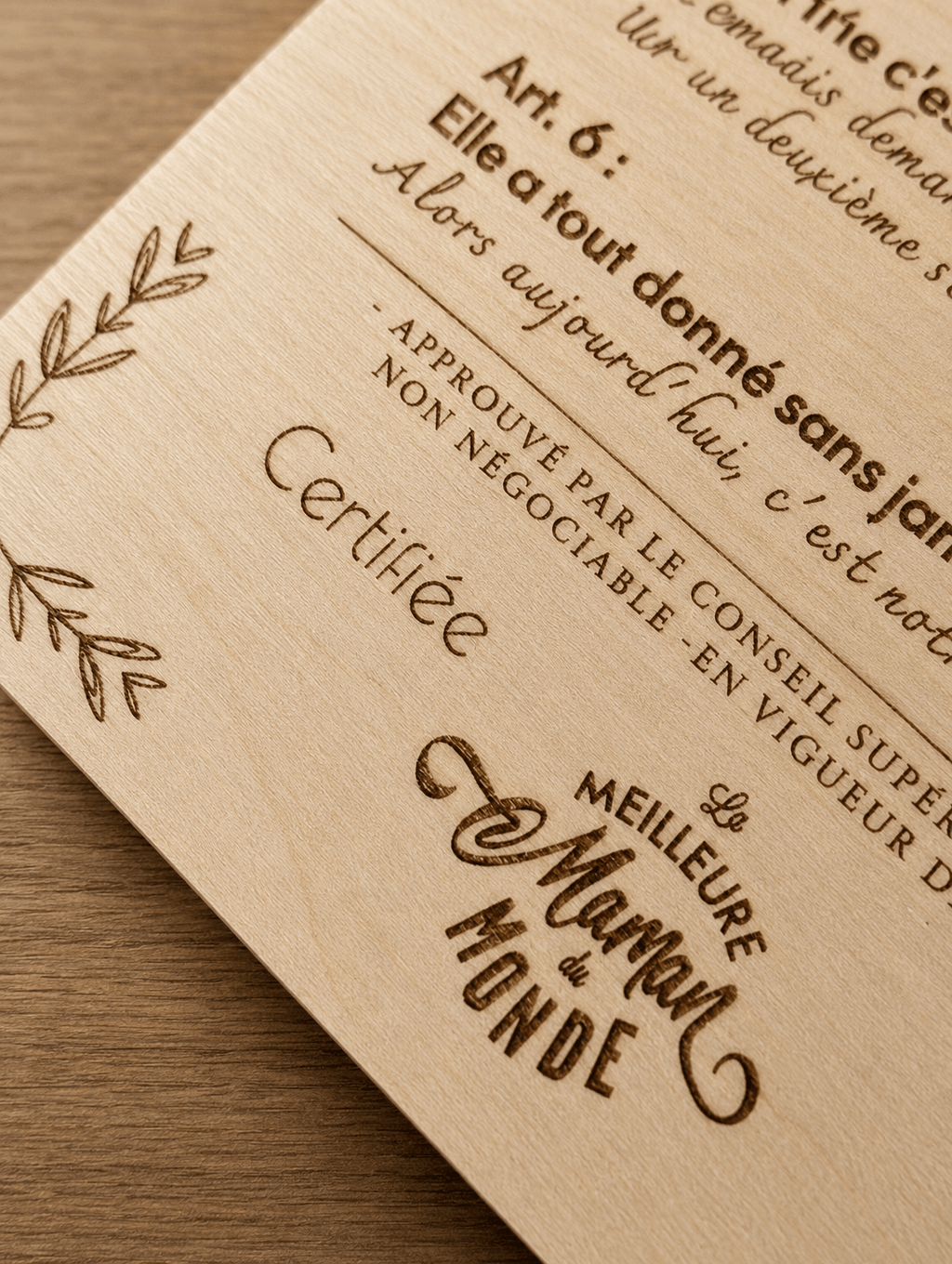 Gros plan de la gravure laser sur plaque bois clair, mention Certifiée La Meilleure Maman du Monde gravée avec précision