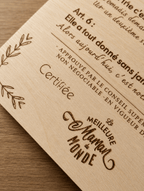 Gros plan de la gravure laser sur plaque bois clair, mention Certifiée La Meilleure Maman du Monde gravée avec précision